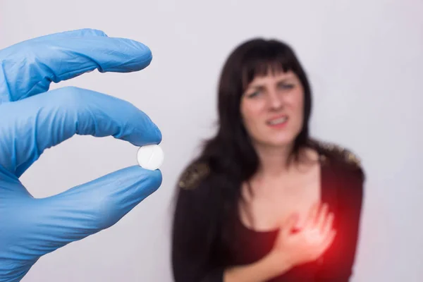 El médico sostiene la píldora en la mano del sistema cardiovascular, niña paciente se para en el fondo y se aferra al corazón, problemas cardíacos, médicos — Foto de Stock