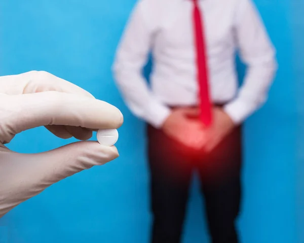 Doctor with a pill in his hand from sexually transmitted diseases, in the background a man clings to the lower abdomen he has genital infection and prostate cancer — Stock Image Doctor with a pill in his hand from sexually transmitted diseases, in the background a man clings to the lower abdomen he has genital infection and prostate cancer Stock Image