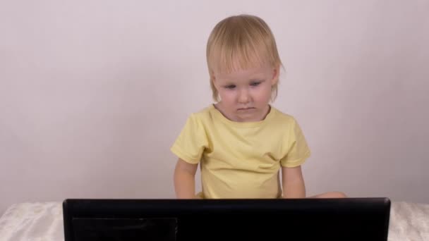 Lilla kaukasiska flicka blonda ser in laptop dator, kvinnliga, barndomen — Stockvideo