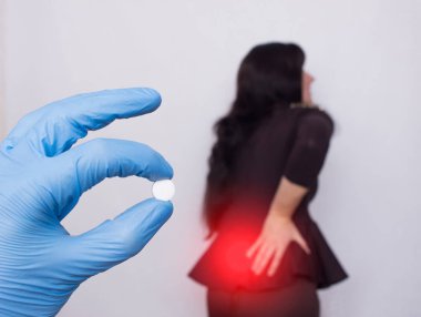 Doktor sırt ağrısı için bir hap bir bel fıtığı ve osteochondrosis, ilaç olan kadının bir arka planda tutar
