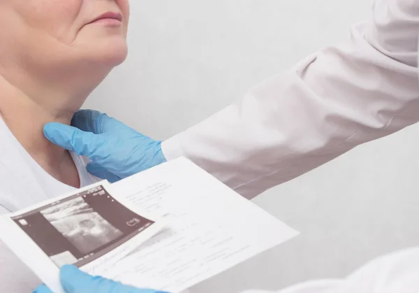 Una mujer está en recepción en el endocrinólogo, el médico observa los resultados de una ecografía de la glándula tiroides, primer plano, médico —  Fotos de Stock