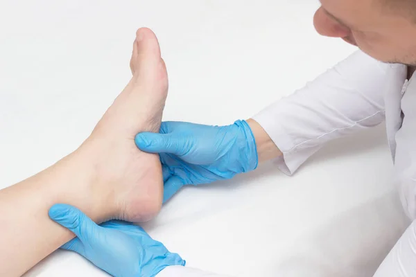 Doktor hastanın ayak topuk spurs, ayak, beyaz arka plan, yakın çekim, plantar fasiit acı ile inceler