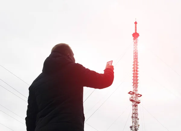 High telecommunication mobile tower from which there is radiation and a man with a mobile phone, poor network, modulation — Stock Photo, Image