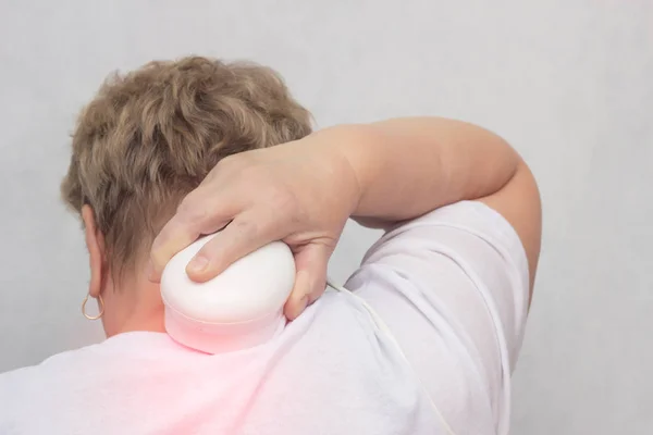 Volwassen vrouw behandelt de cervicale wervelkolom met behulp van magneetveld fysiotherapie, magnetisme, witte achtergrond, osteochondrose — Stockfoto