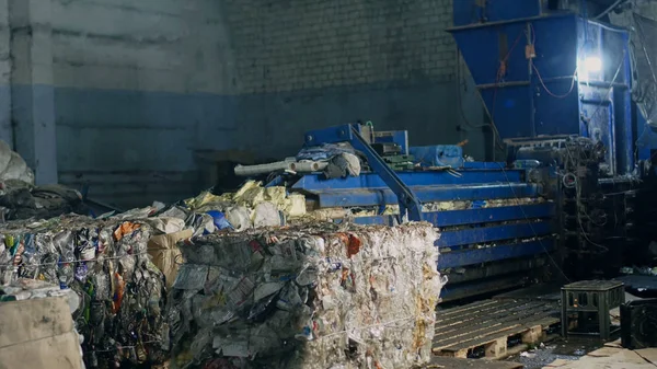 Press at waste recycling plant for pressing plastic and cardboard waste, processing