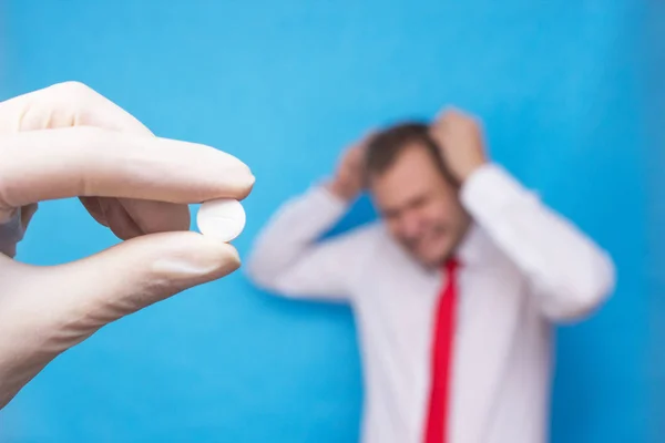 The doctor is holding a pill for psychosis, in the background is a man who has a mental disorder, psychosis — Stock Photo, Image