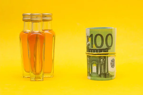 Malé láhve s alkoholem a euro peníze, příjmy z obchodu s alkoholem, zvýšení ceny, detail — Stock fotografie