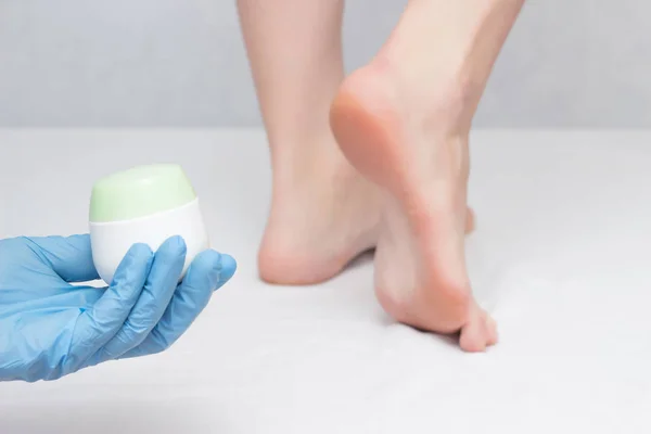 Doctor holds healing heel cream, against fungus and dry skin, close-up, white background, dermatitis, medicinal