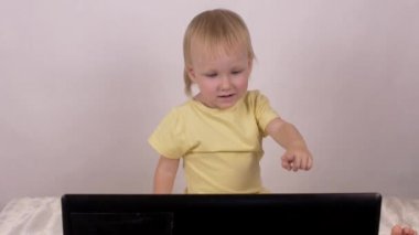 Küçük beyaz kız oynar ve bilgisayar laptop, duyguları ile çalış