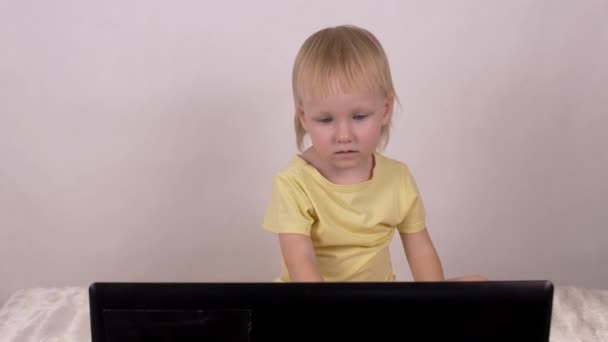 Malá blondýnka kavkazské dívka vypadá do přenosného počítače, Žena, dětství — Stock video