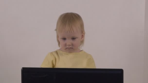 Una bambina gioca e gioca con un computer portatile, mostra diverse emozioni sul suo viso, slow-mo — Video Stock