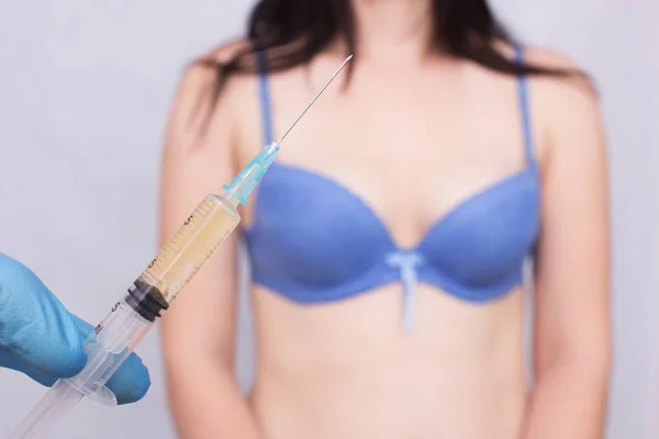Médecin tient une seringue et effectue une injection de lipofilling sur l'augmentation mammaire d'une fille, cosmétique — Photo