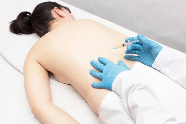 A doctor makes a shot with plasma in the spine of a girl patient who has back problems, treatment with plasma therapy — Stock Image A doctor makes a shot with plasma in the spine of a girl patient who has back problems, treatment with plasma therapy Stock Picture