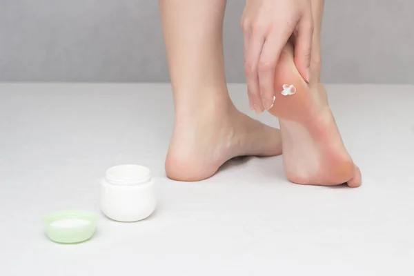 Kız onun arkasından çatlaklar karşı krem şifa smear ve kuru cilt, beyaz arka plan, yakın çekim, Dermatoloji