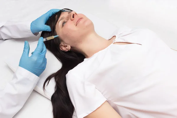 A doctor makes a plasma-lifting young patient to remove acne from the face and improve skin quality, plasma therapy, procedure