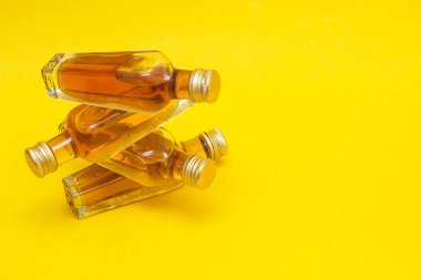 Small bottles with alcohol on a yellow background, close-up, copy space, purchase