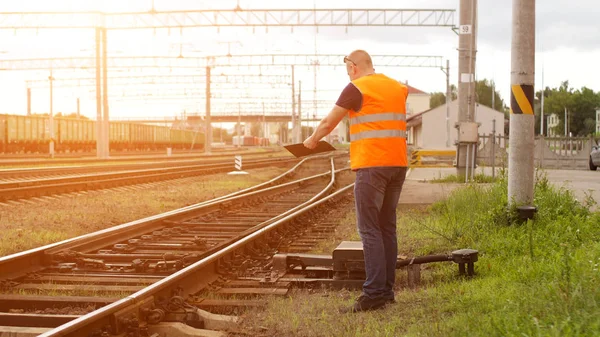 O chefe do mal na ferrovia inspeciona o mecanismo de comutação ferroviária e grita ao telefone — Fotografia de Stock