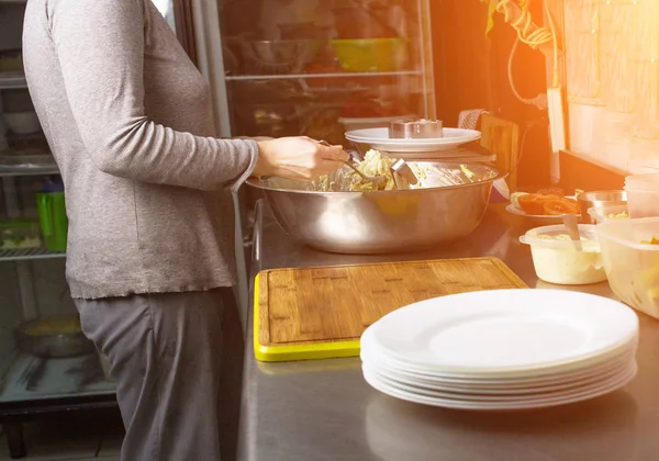 Повар на кухне весит порции салата на весах в граммах и обслуживает стол, кухонный уголок — стоковое фото