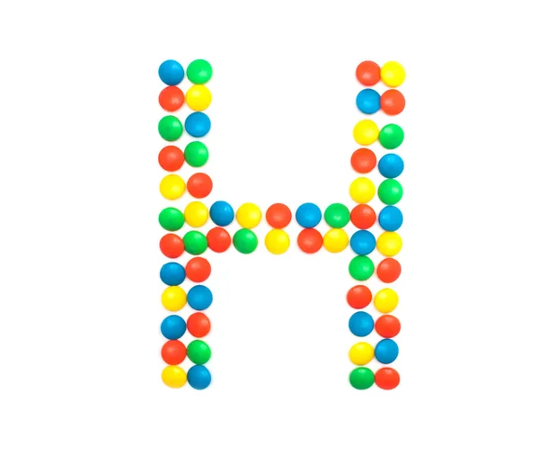 Multi-colored vitamins pills that are lined with the letter Vitamin H, close-up