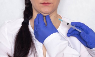 Doktor bir beyaz kız çift çene lipolytic enjeksiyon bir beyaz arka plan, tıbbi, yakın çekim verir.