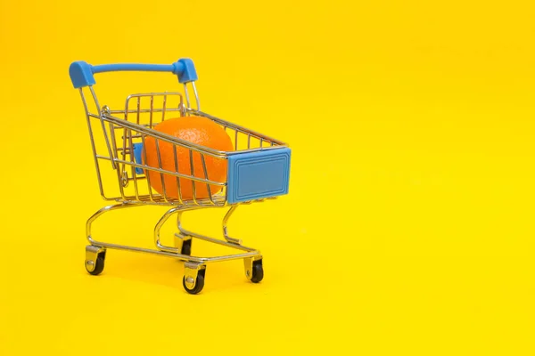 Mandarim em um carrinho de compras em um fundo amarelo, close-up, exportação de alimentos e frutas no exterior — Fotografia de Stock