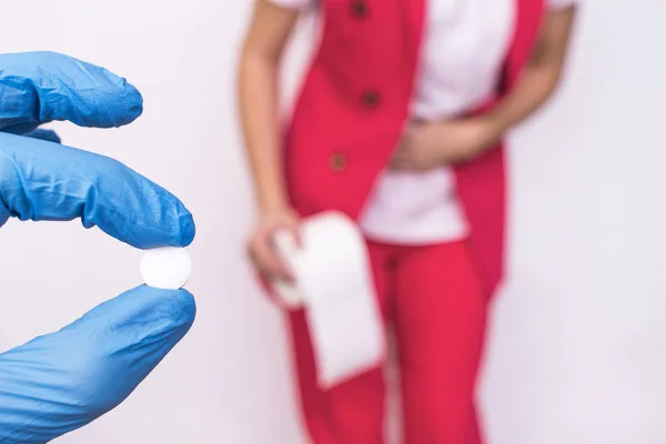 Γιατρός κρατώντας ένα χάπι στο χέρι της το φόντο ενός κοριτσιού με χαρτί τουαλέτας, έννοια χάπια για διάρροια και εντερικά αναστατωμένος — Φωτογραφία Αρχείου