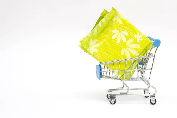 Almohadillas femeninas en un carrito de compras sobre un fondo blanco, concepto de compras de higiene personal, primer plano, espacio para copiar —  Fotos de Stock