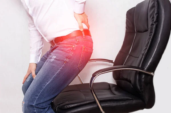 Un hombre en la oficina sosteniendo su espalda desde una silla, el concepto de dolor de espalda, hernia intervertebral y osteocondrosis de la columna vertebral — Foto de Stock