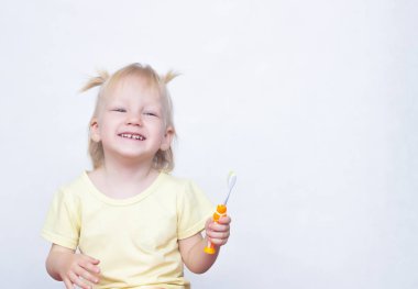 Küçük kızım 2 yaşında pigtails saçında ile gülüyor ve kopya alanı, beyaz bir arka plan dişlerini fırçalar