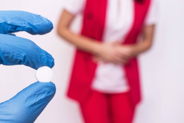 Doktor bir hap elinde tutarak karın ağrısı olan bir kadının arka planı ve şişkinlik, tıp, antispasmodic