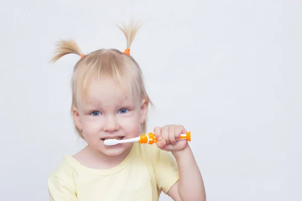 Mała dziewczynka 2 latka z warkoczykami na jej włosy myje zęby i patrzy w kamerę, miejsce, twarz — Zdjęcie stockowe
