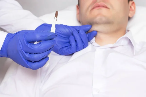 Ο γιατρός κρατάει ένα χειρουργικό νυστέρι στο φόντο του προσώπου του ένας άνθρωπος με ένα διπλό πηγούνι. Έννοια της πλαστικής χειρουργικής στην κοσμετολογία, anaplasty — Φωτογραφία Αρχείου