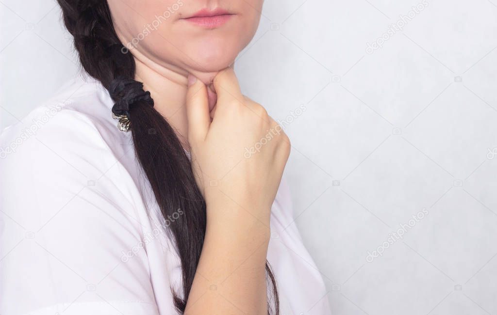 The girl holds her hand behind the double chin on a white background, copy sapce