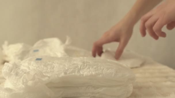 Mother collects baby diapers on the table in a pile, background, close-up — Stock Video