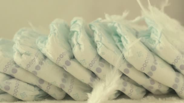Les plumes blanches délicates tombent sur les couches pour bébés, le concept de confort et de légèreté, au ralenti — Video