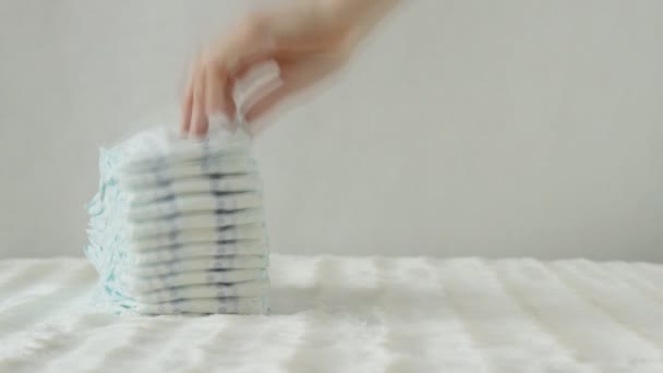 Madre prende una pila di pannolini per bambini su uno sfondo bianco, spazio di copia, protezione — Video Stock
