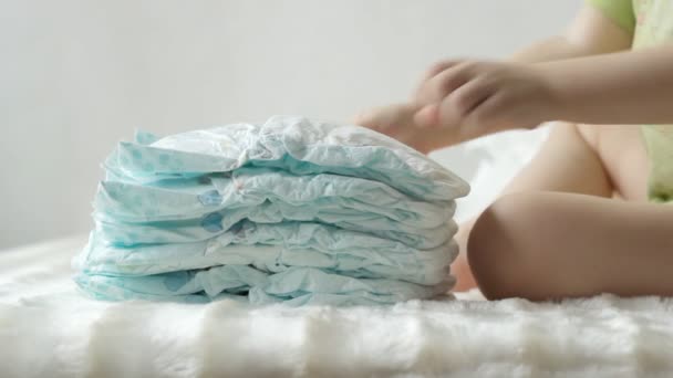 L'enfant joue avec les couches de bébé dans une pile, bébé, fond, couche — Video