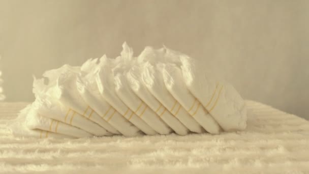 Белые перья падают на концепцию детских подгузников чистоты, легкости и комфорта, замедленного движения, копирования пространства, защиты — стоковое видео