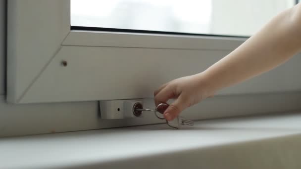 The child is trying to open the pvc window with a hand against the loss of children, a protective lock, safety, child — Stock Video