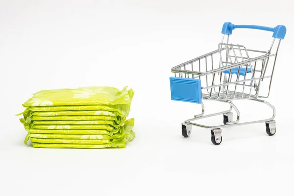 Almofadas femininas em um carrinho de compras em um fundo branco, conceito de compras de higiene pessoal, close-up, espaço de cópia — Fotografia de Stock