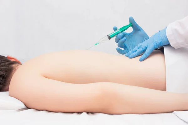 The doctor conducts a procedure for young girl injections of chondroprotector and ozone therapy against intervertebral hernia, inflammation and back pain, copy space, spondylosis — Stock Image The doctor conducts a procedure for young girl injections of chondroprotector and ozone therapy against intervertebral hernia, inflammation and back pain, copy space, spondylosis Stock Photo
