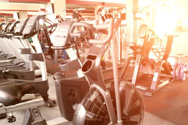 Yeni modern kardiyovasküler ve ağırlık eğitim donanımları, kondisyon bisikletleri ve eliptik, günbatımı, arka plan ile spor salonu