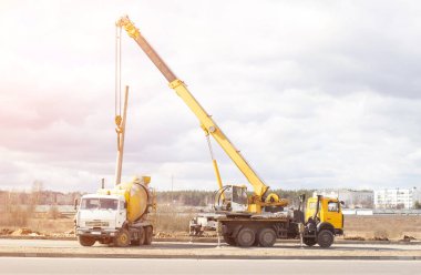 Yükleme ve aydınlatma lambaları kullanarak bir kamyon vinç ve çimento kamyonu, güneş, kopya yeni yol inşaatı uzay, Bina