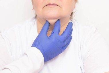 Bir plastik cerrah, kırışıklıkları ve çift çeneleri, beyaz arka plan, kozmetolojist sıkmak ve kurtulmak için yaşlı bir beyaz kadın inceler