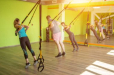 Spor salonunda insanlar Trx döngüleri üzerinde meşgul ve el kaldırma bir egzersiz yürütmek, kasları güçlendirmek için, kopya alanı, bulanık