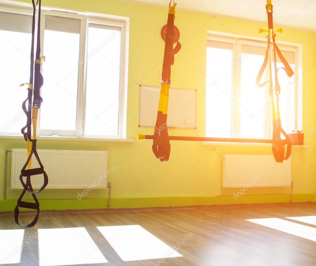 Modern new gym in the fitness center to practice a new sport of the TRX loop, the sun in the window, workout