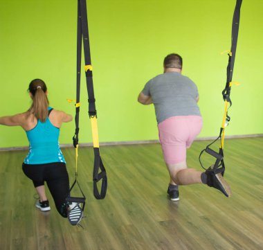 Bir adam ve bir kız Trx döngüleri üzerinde egzersizler Bulgar split-squat, kalça, bacak ve kuadriseps kasları güçlendirilmesi performans meşgul