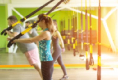Spor salonunda insanlar Trx döngüleri meşgul ve triceps bir uzatma egzersiz yapmak, kas güçlendirme, bulanık, gün batımı