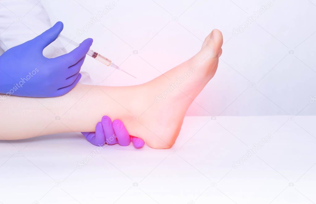 The doctor makes an injection into the ankle joint of the patient in plasma therapy to eliminate inflammation and pain, relieve edema, copy space
