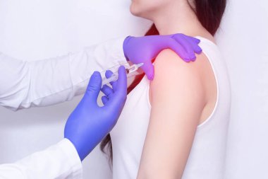 Doctor makes an injection of blockade of chondroprotector and anti-inflammatory drug in the girls sore shoulder, white background, close-up, ozone therapy clipart